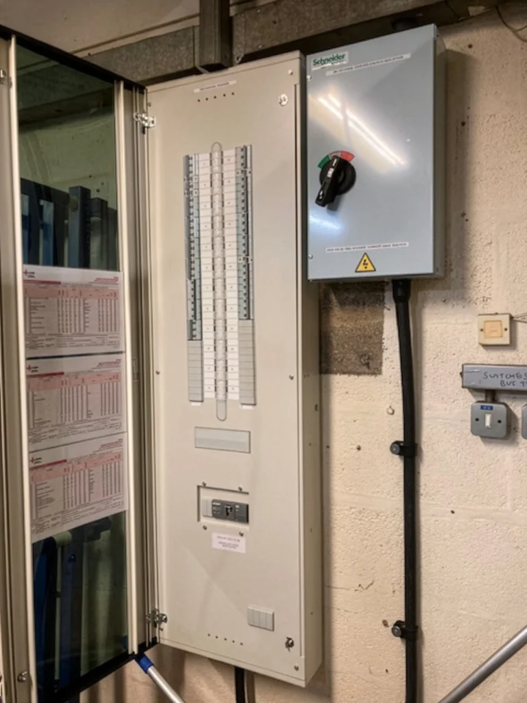 Tall white industrial distribution board newly mounted on a workshop wall.